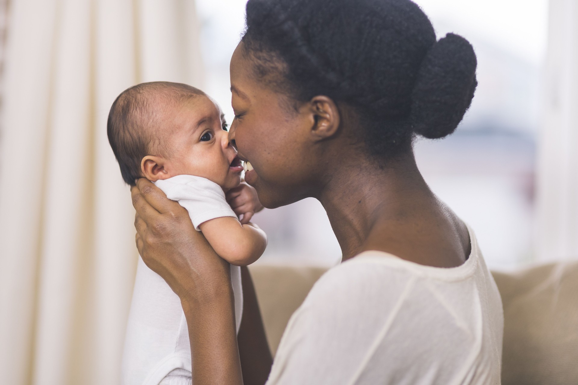 Beautiful African American mother holds newborn baby in the living room